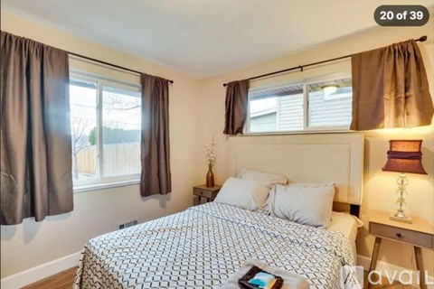 A bedroom with a large bed and a window with curtains.