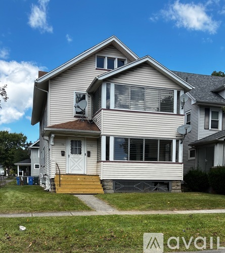 A two-story house with a white door and a brown front porch.