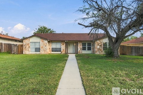 A house with a brown roof and stone exterior is surrounded by a well-kept lawn and a sidewalk leading to the front door.