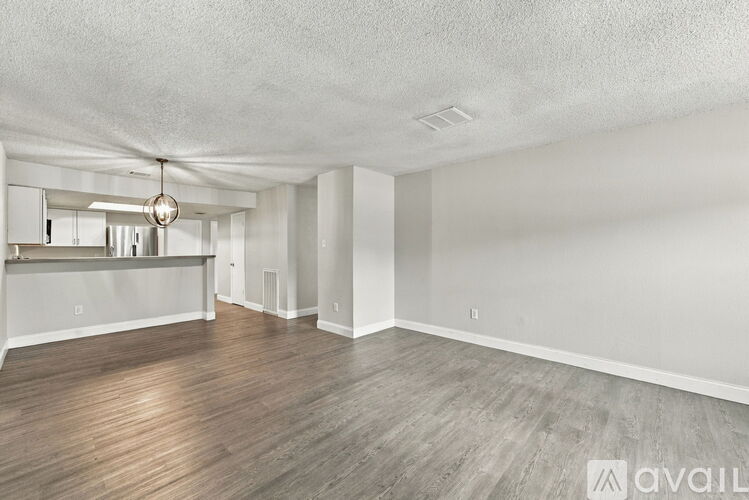 A spacious room with wooden flooring and a hanging light fixture.