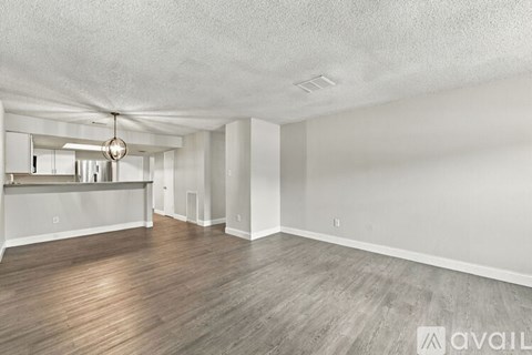 A spacious room with wooden flooring and a hanging light fixture.