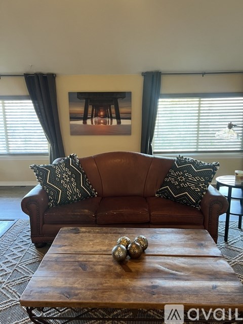 A brown leather couch with two patterned pillows sits in a living room.
