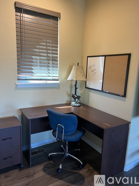 A room with a desk, chair, and lamp.