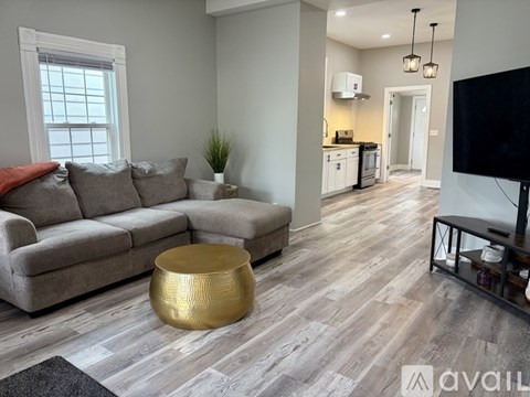 A living room with a grey couch and a gold coffee table.