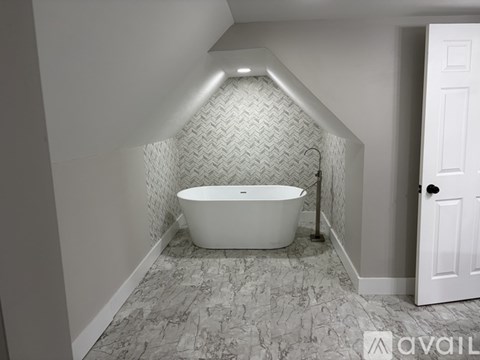 A white bathtub in a bathroom with a marble floor and a white door.