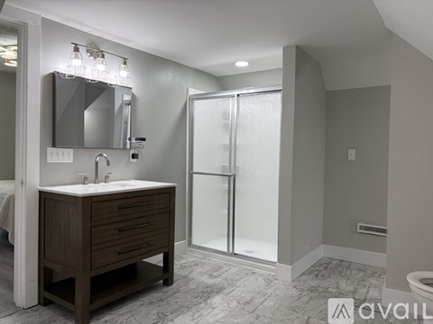 A bathroom with a wooden vanity and a walk-in shower.
