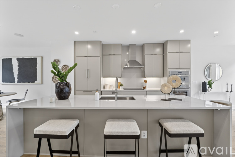 A modern kitchen with a white countertop and bar stools.