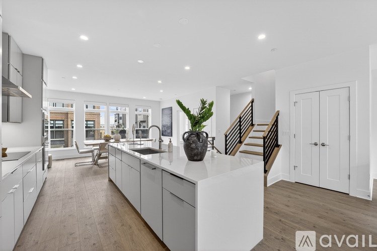 A modern kitchen with white cabinets and a wooden floor.