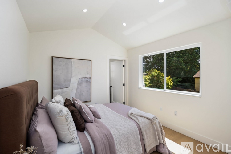 A bedroom with a large bed and a window overlooking trees.