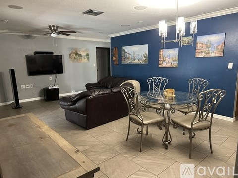 A living room with a brown leather couch, a glass table, and a television.