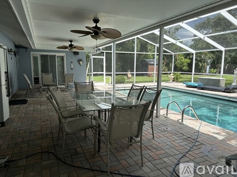 A patio with a table and chairs overlooking a pool.