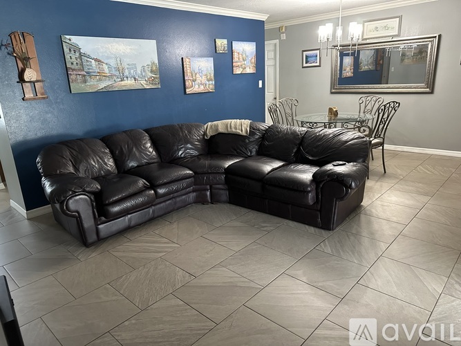 A black leather sofa in a living room with a grey tiled floor.