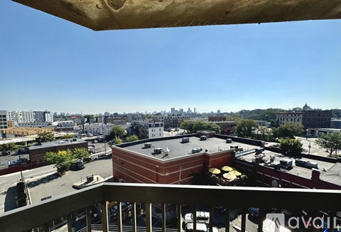 A view from a balcony overlooking a cityscape with buildings and a clear blue sky.