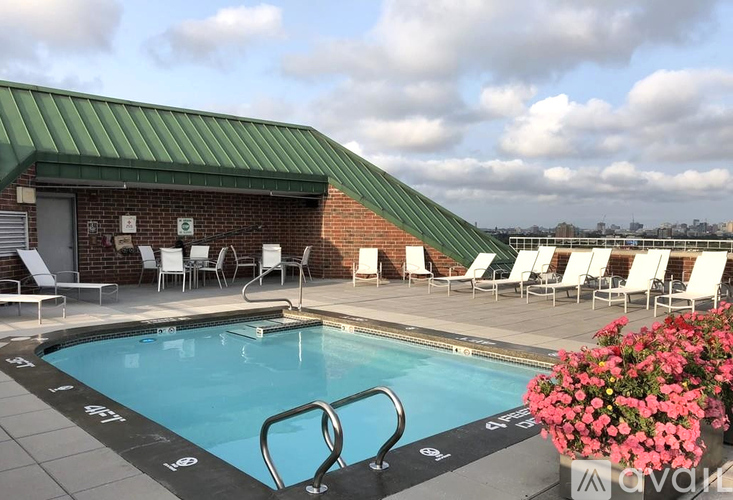 A pool with a green roof and white chairs around it.