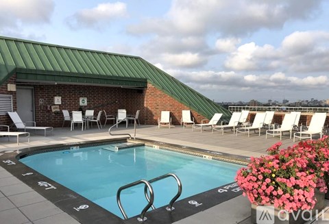 A pool with a green roof and white chairs around it.