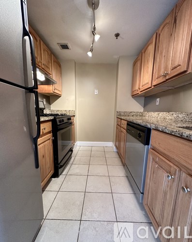A kitchen with a refrigerator on the left and cabinets on the right.