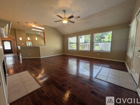 A spacious room with wooden flooring and a ceiling fan.
