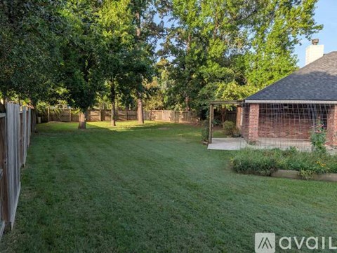 A backyard with a fence, trees, and a small building.