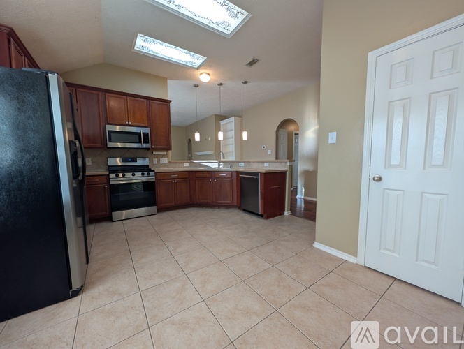 A kitchen with a black refrigerator and wooden cabinets.