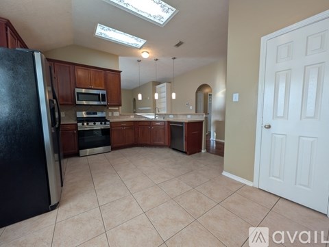 A kitchen with a black refrigerator and wooden cabinets.