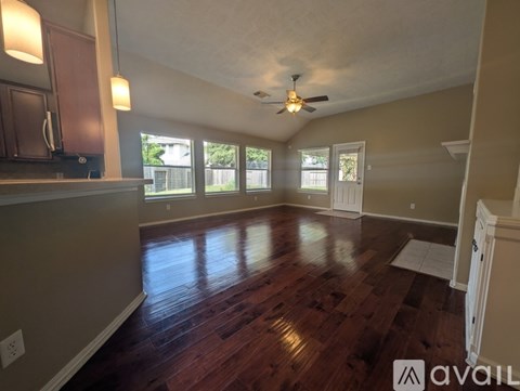 A spacious living room with hardwood floors and a ceiling fan.