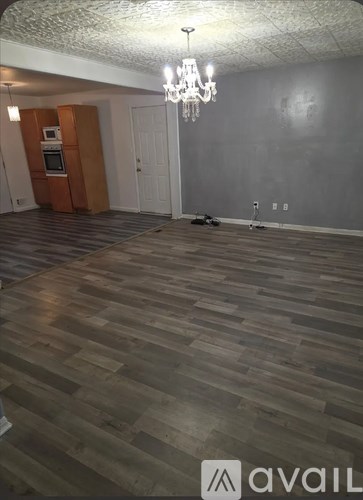 A room with wooden flooring and a chandelier.