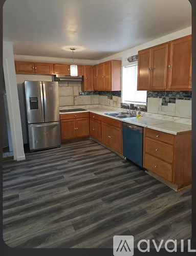 A kitchen with wooden cabinets and a stainless steel refrigerator.