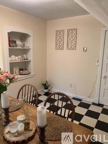 A dining room with a checkered floor and a wooden table set for two.