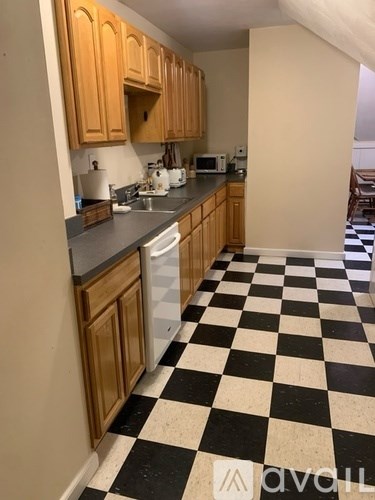 A kitchen with wooden cabinets and a checkered floor.