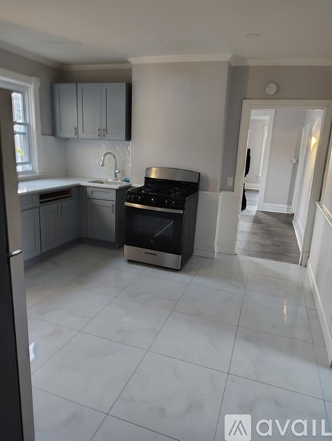 A kitchen with a black stove top oven and a white tiled floor.