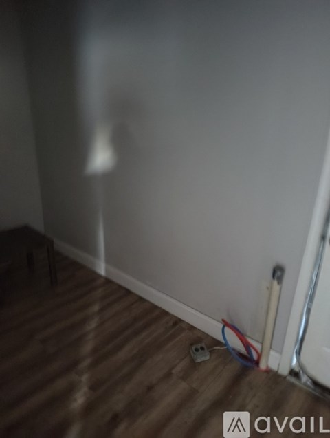 A room with a wooden floor and a white wall.