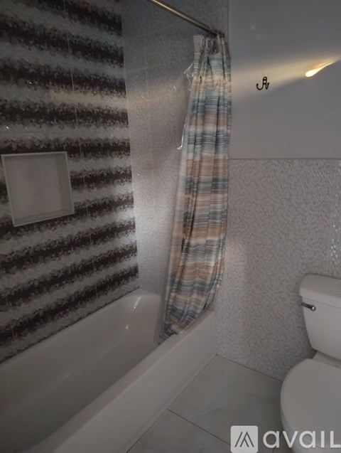 A bathroom with a toilet, a shower curtain, and a light switch.
