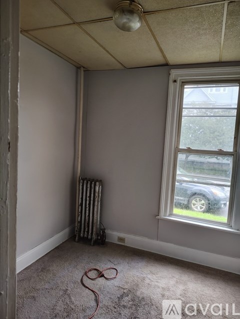 A room with a window and a radiator on the floor.