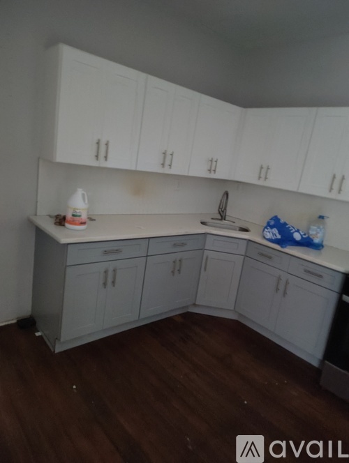 A kitchen with white cabinets and a wooden floor.