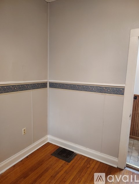 A room with a wooden floor and a wall with a blue and black tile border.