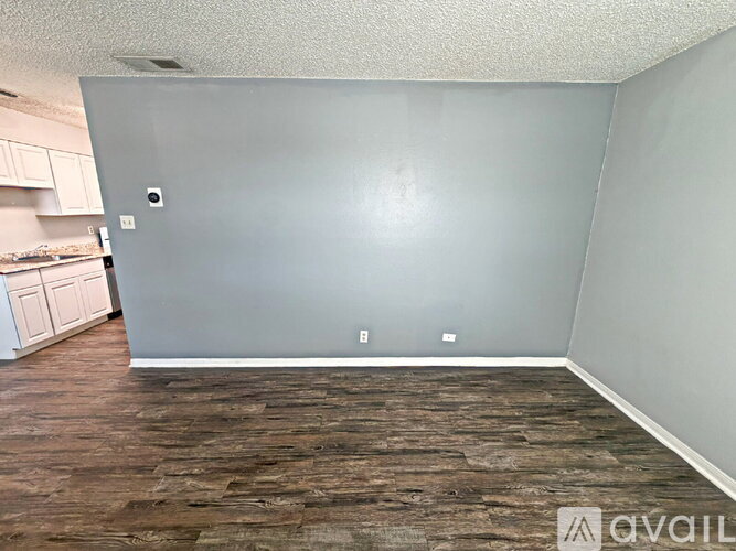 A room with wooden flooring and a grey wall.