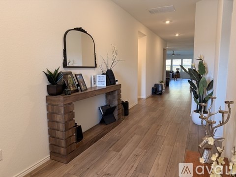 A long hallway with a wooden floor and a mirror on the wall.