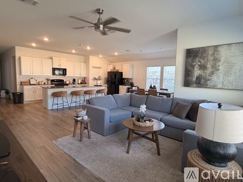 A modern living room with a grey couch, wooden coffee table, and a ceiling fan.