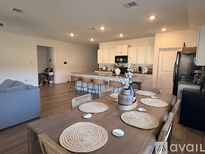 A modern kitchen with a dining table and chairs in the middle of the room.