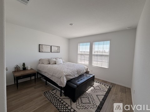 A bedroom with a bed, bench, and a small table with a plant on it.