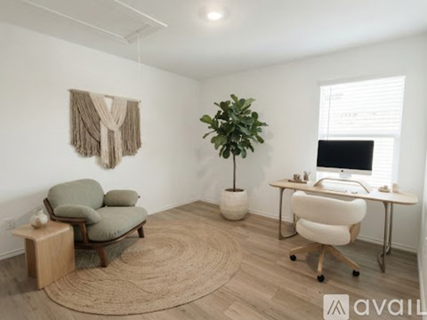 A room with a chair, a desk, and a plant.