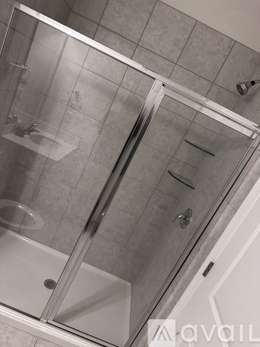 A shower with a glass door and a glass shelf.