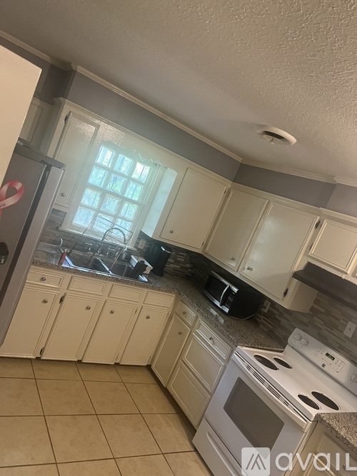 A kitchen with white cabinets and appliances.