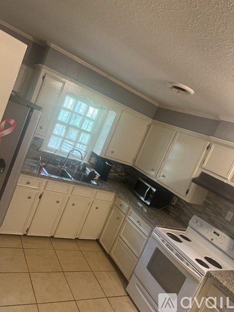A kitchen with white cabinets and appliances.