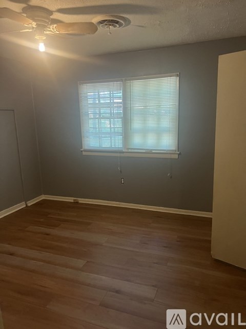 A room with a ceiling fan and a window with blinds.