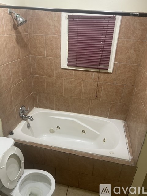 A bathroom with a toilet, tub, and window.