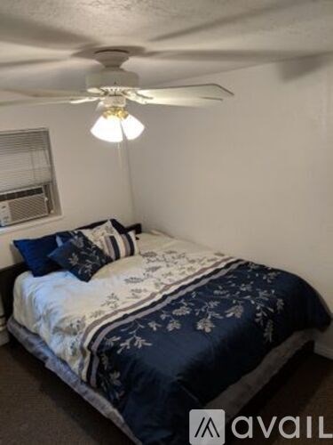 A bedroom with a bed covered in a blue and white comforter.