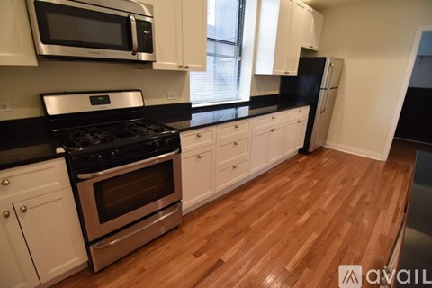 A kitchen with wooden floors and black countertops.
