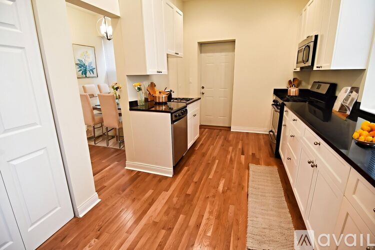 A kitchen with wooden floors and white cabinets.