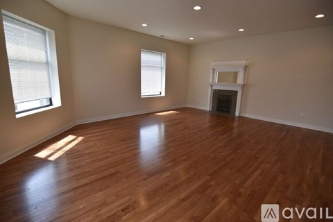 A spacious room with wooden flooring and a fireplace.